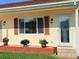 Inviting entryway featuring a decorative glass door, colorful flower pots, and brown shutters at 17574 Se 95Th Ct, Summerfield, FL 34491