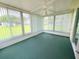 Sunroom with walls of windows, a ceiling fan, and serene views of the outdoors and green flooring at 17574 Se 95Th Ct, Summerfield, FL 34491