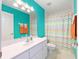 Bright bathroom with a white vanity, a colorful shower curtain, and teal painted walls at 2 Hemlock Trace Run, Ocala, FL 34472