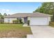 Lovely home featuring a two-car garage, attractive landscaping, and a welcoming blue front door, creating a charming curb appeal at 2 Hemlock Trace Run, Ocala, FL 34472