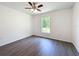 Bright bedroom with hardwood floors, a ceiling fan, and a window overlooking a lush, green landscape at 22777 Sw Beach Blvd, Dunnellon, FL 34431