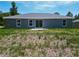 Rear exterior view of a home with sliding glass doors, lots of space in the backyard, and a gray facade at 22777 Sw Beach Blvd, Dunnellon, FL 34431