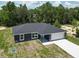 A modern exterior of the home with a gray facade, a clean driveway, and an attached two-car garage at 22777 Sw Beach Blvd, Dunnellon, FL 34431