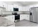 Modern kitchen featuring stainless steel appliances, white cabinets, and elegant granite countertops at 22777 Sw Beach Blvd, Dunnellon, FL 34431