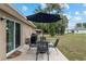 View of an outdoor patio with table and chairs set under a large umbrella and a grill nearby at 2690 Sw 154Th Ln, Ocala, FL 34473