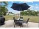 Outdoor patio with a table and chairs set under a large umbrella and a grill nearby at 2690 Sw 154Th Ln, Ocala, FL 34473