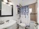 Bathroom with a white sink, toilet, tub with shower and blue and white decorative shower curtain at 3880 Sw 6Th Ave, Ocala, FL 34471