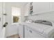 Laundry room with white appliances, overhead cabinets and shelves, and a window at 3880 Sw 6Th Ave, Ocala, FL 34471