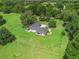 Aerial view of fenced estate home on manicured lawn featuring a stone drive and lush greenery at 402 Sw 127Th Pl, Ocala, FL 34473