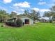 View of exterior of green storage barn on green lawn with adjacent home in the background at 402 Sw 127Th Pl, Ocala, FL 34473