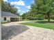 Paver driveway leading to a carport with a vehicle parked, surrounded by lush green lawn and mature trees at 402 Sw 127Th Pl, Ocala, FL 34473