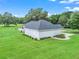 Exterior view of the home surrounded by a lush green lawn, shrubs, and secure storm shutters at 402 Sw 127Th Pl, Ocala, FL 34473