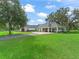 An expansive home featuring a covered portico and lush green lawn with a long paved driveway at 402 Sw 127Th Pl, Ocala, FL 34473