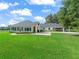 Well-manicured front yard featuring a circular driveway, lush lawn, and a charming home exterior at 402 Sw 127Th Pl, Ocala, FL 34473