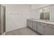 Bright bathroom featuring double vanity with granite countertops and grey cabinets, as well as a glass enclosed shower at 4892 Nw 39Th Loop, Ocala, FL 34482