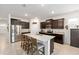 Kitchen island with seating, dark cabinets, stainless appliances, and granite countertops at 6265 Sw 88Th Loop, Ocala, FL 34476