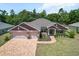 Charming home with a three-car garage, brick driveway, and lush front yard landscaping at 6680 Sw 179Th Court Rd, Dunnellon, FL 34432
