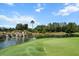 Scenic golf course view with a water feature, lush greenery, and clear blue skies at 6680 Sw 179Th Court Rd, Dunnellon, FL 34432
