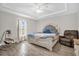 Bright main bedroom featuring a large bed, tray ceiling with fan, and wood-look flooring at 7 Pecan Drive Ter, Ocala, FL 34472