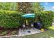 Backyard featuring a stone patio with seating and grill surrounded by lush landscaping, perfect for outdoor entertaining at 7263 Sw 99Th Cir, Ocala, FL 34481