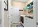 Bright laundry room with a washer and dryer, shelves and hooks for storage, and a patterned area rug at 7263 Sw 99Th Cir, Ocala, FL 34481