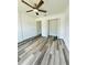 A spacious bedroom boasting wood-look floors and an open closet with bi-fold doors at 7292 Hemlock Loop, Ocala, FL 34472