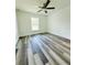 A comfortable bedroom offering wood-look flooring, a ceiling fan, and a bright window at 7292 Hemlock Loop, Ocala, FL 34472