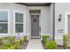 Inviting entryway featuring a gray door, a festive wreath, and manicured landscaping at 8809 Sw 61St Loop, Ocala, FL 34481