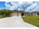Charming single-Gathering home with lush green lawn, large driveway, and beautiful landscaping under a bright blue sky at 9777 Sw 63Rd Loop, Ocala, FL 34481