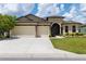 Well-maintained home with a two-car garage, stone accents, manicured lawn, and a welcoming entrance under a blue sky at 9777 Sw 63Rd Loop, Ocala, FL 34481