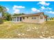 The back exterior of the home has neutral siding, lush lawn, and sunroom at 10520 Sw 85Th Ter, Ocala, FL 34481