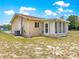 Tan home's back exterior showcasing a sunroom and well-maintained lawn, perfect for outdoor enjoyment at 10520 Sw 85Th Ter, Ocala, FL 34481