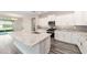 Open-concept kitchen with white cabinets, gray backsplash, stainless steel appliances, and a large island at 10625 Sw 98Th Pl, Ocala, FL 34481