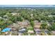 An aerial view shows homes nestled among mature trees in a neighborhood with a clear blue sky above at 1520 Ne 17Th Ave, Ocala, FL 34470