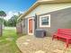 A landscaped backyard featuring an air conditioner, pebble ground cover, and a red bench at 1520 Ne 17Th Ave, Ocala, FL 34470