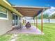 A covered backyard patio with string lights, a lawn mower, and an adjacent grassy yard at 1520 Ne 17Th Ave, Ocala, FL 34470