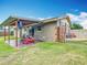 A covered backyard patio with a lawn mower and access to the grassy backyard and gate at 1520 Ne 17Th Ave, Ocala, FL 34470