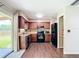 Bright kitchen features wooden cabinets, black appliances, wood-look flooring and access to the porch at 1520 Ne 17Th Ave, Ocala, FL 34470