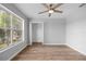 This bedroom has wood floors, a ceiling fan, a large window, and gray walls at 1628 Se 29Th Ter, Ocala, FL 34471