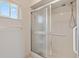 Walk-in shower featuring glass doors, safety bar, and a hand-held shower head at 17890 Se 96Th Ct, Summerfield, FL 34491