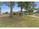 Residential home with mature shade trees and a large front yard with a driveway and an adjacent storage shed at 2819 Ne 32Nd Pl, Ocala, FL 34479