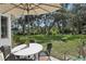 Relaxing backyard patio with a table, chairs, umbrella, and landscaped green space at 36 Gordon Ct, Leesburg, FL 34788