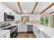 Modern kitchen boasts stainless steel appliances, white cabinets, solid surface countertops, and beamed ceilings at 361 Oak Lane Drive Dr, Ocala, FL 34472
