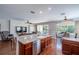 Open-concept kitchen boasts a breakfast bar, wood cabinets, stainless steel appliances, and views of the living and dining areas at 6984 Sw 94Th Ct, Ocala, FL 34481