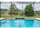 Serene screened-in pool with a tranquil waterfall feature and lush greenery in the backdrop at 6984 Sw 94Th Ct, Ocala, FL 34481