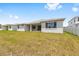 View of spacious backyard showing house exterior with covered patio, lush green lawn, and home design at 7638 Sw 60Th St, Ocala, FL 34474