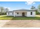 A rear view of a single-story home with a covered patio, green lawn, and french doors at 8200 Sw 125Th Court Rd, Dunnellon, FL 34432