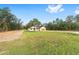 Single-story home on a sprawling green lawn, with a long driveway, and covered front porch at 8200 Sw 125Th Court Rd, Dunnellon, FL 34432