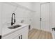 Well-lit laundry room with white cabinets, stylish faucet, and wood-look vinyl flooring at 8200 Sw 125Th Court Rd, Dunnellon, FL 34432