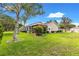 A lush green backyard featuring the property's beige siding, a screened in patio, and landscaping at 9131 Se 135Th St, Summerfield, FL 34491